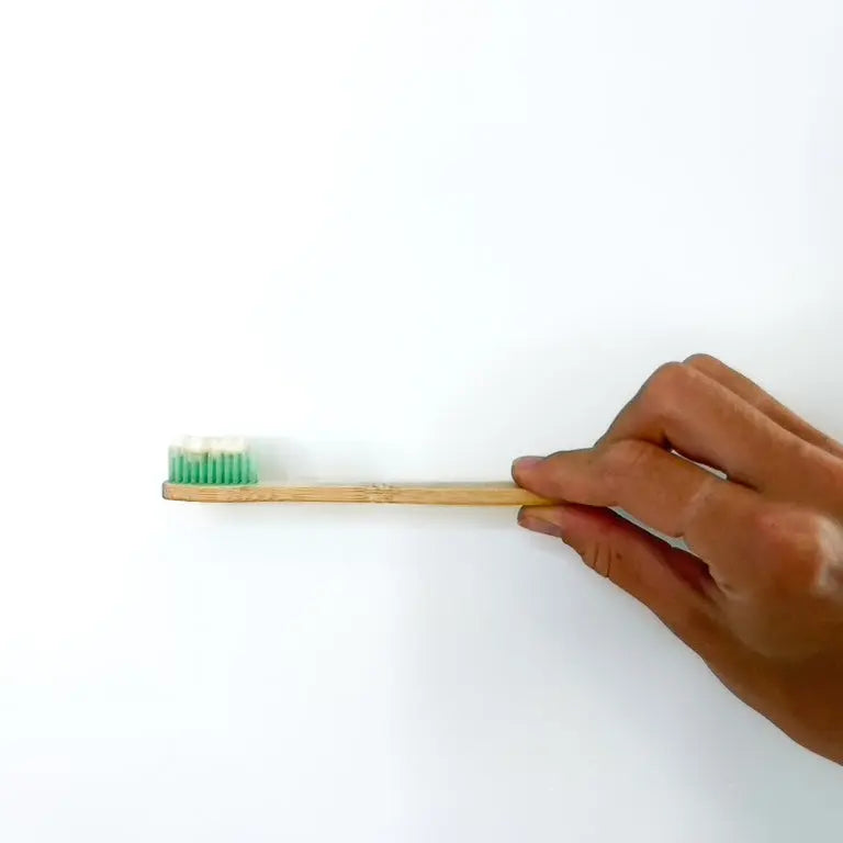 Person holding bamboo toothbrush with natural toothpaste on it.