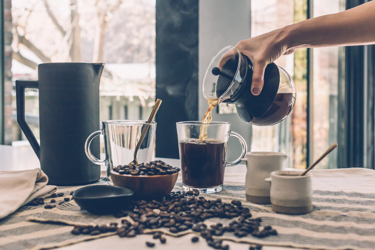 Person pouring hot coffee plus coffee beans, sugar and cream. Coffee lovers dream.