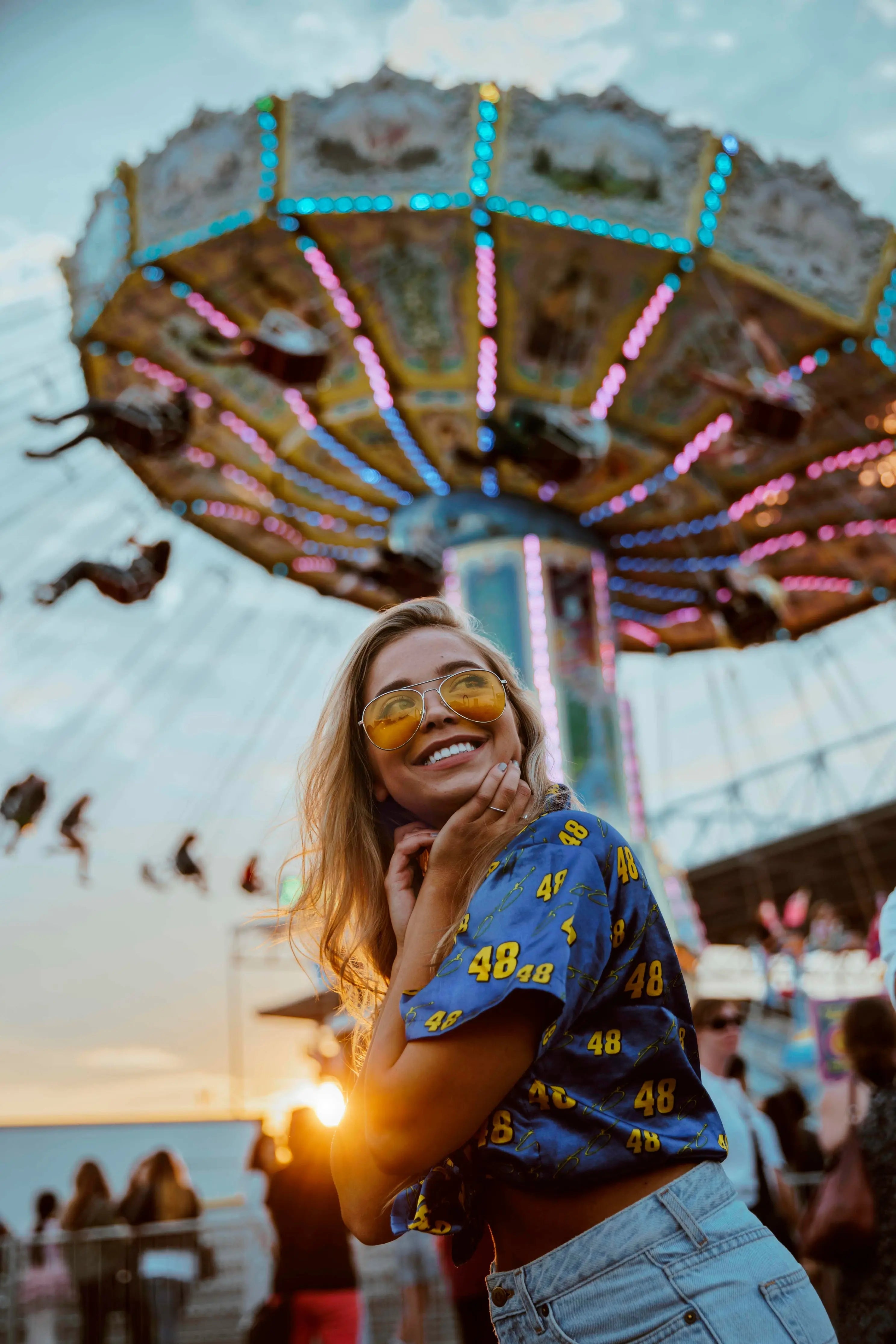 Woman smiling with white teeth in front of an amusement park ride.
