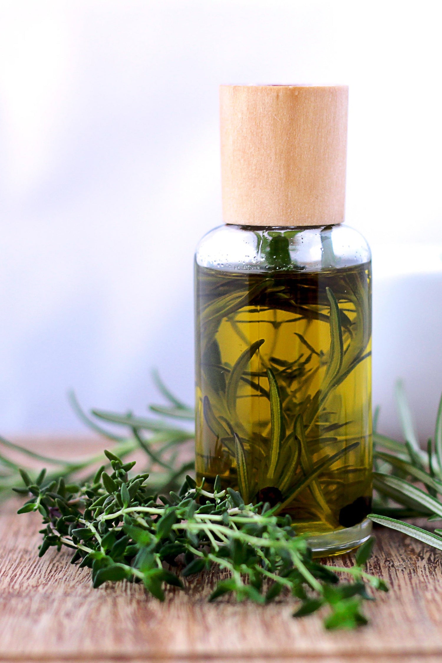 Image of essential oil in bottle tabletop next to basil